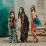 3 women in black and green dress standing on gray concrete floor